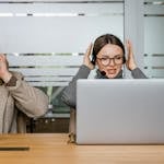 Two customer support agents using laptops and headsets in modern office.